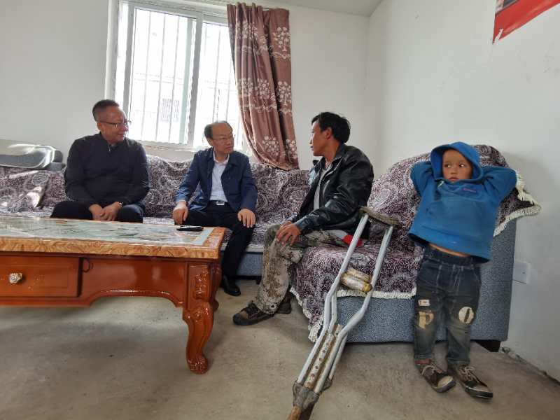 图片：周长奎（左二）在肢体一级残疾人吉力子呷家入户调研