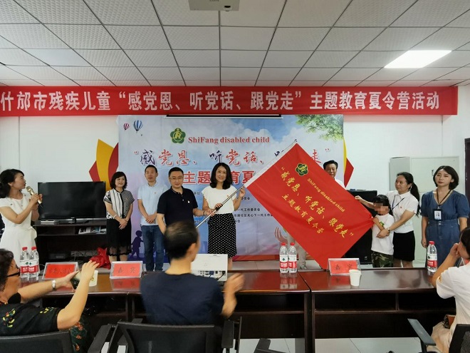 图片：市残联理事长刘庆莉、市方亭街道办书记王云海为残疾儿童夏令营活动授开营旗