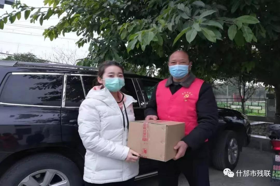 什邡市残联抗疫工作人员杜卓将沉甸甸的消毒液送到村干部手中