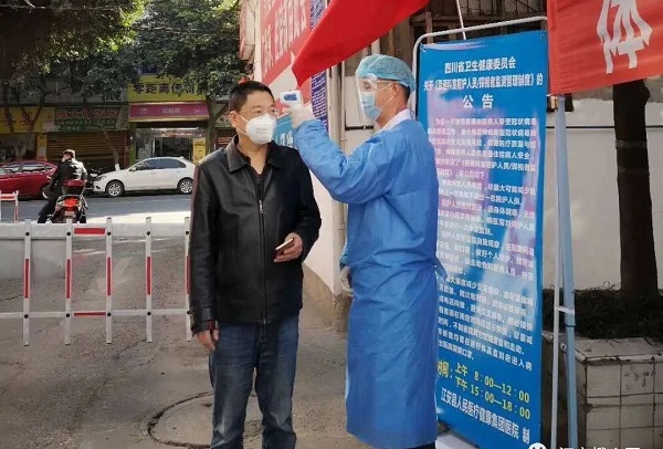 图片：姜方成在江安县人民医院站点为过往群众测量体温